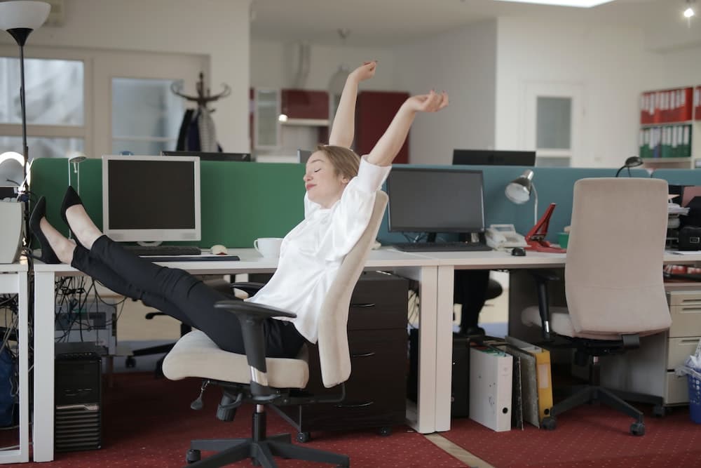 Woman stretching her arms and legs while sitting in an office chair